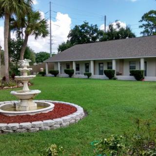 A well-maintained garden with a fountain and a building in the background.