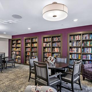 A cozy library room with bookshelves, tables, and chairs for reading.