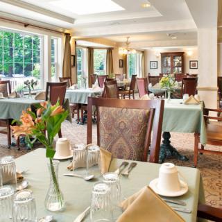 Elegant dining area with neatly arranged tables and chairs, surrounded by large windows.