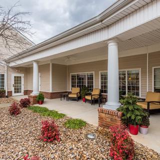 A well-maintained patio with seating and decorative plants in front of a building.