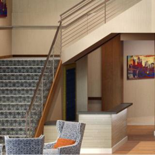 A modern lobby interior featuring a staircase, seating area, and artwork on the wall.