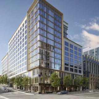 A modern office building with a glass facade located on a busy city street corner.