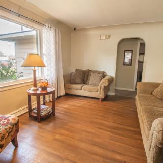 A cozy living room with a large window, two sofas, a lamp on a side table, and hardwood flooring.
