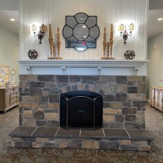A beautifully designed stone fireplace with elegant decor, featuring a large mirror and wall sconces.