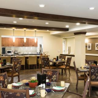 A cozy dining area with neatly arranged tables and chairs, featuring warm lighting and elegant decor.