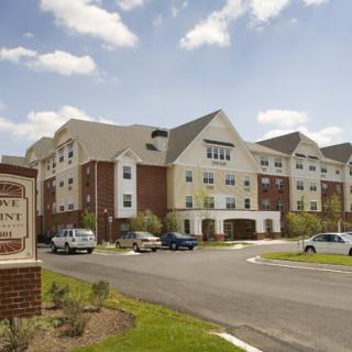 A modern residential apartment complex with a parking lot under a partly cloudy sky.