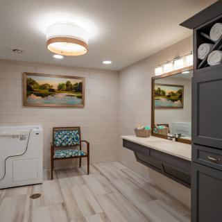 A modern bathroom featuring a vanity mirror, laundry machine, and artwork on the wall.
