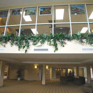 A spacious lobby area featuring large windows and greenery with seating arrangements.