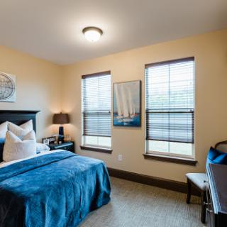 A cozy and well-lit bedroom featuring blue bedding and stylish decor.