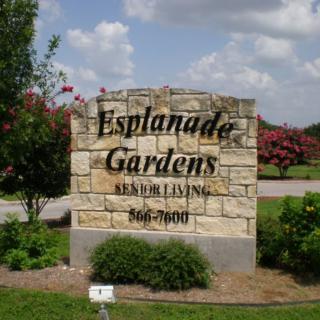 A stone sign for Esplanade Gardens surrounded by greenery.