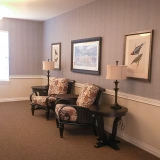 A cozy living area with two armchairs, a wooden table, and framed artwork on the walls.