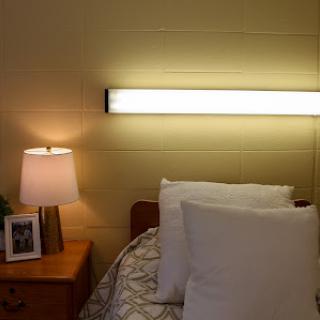 A cozy bedroom setup featuring a neatly made bed with pillows, a bedside lamp, and a photo frame on the nightstand.