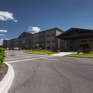 A modern building with a driveway under a clear blue sky.