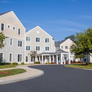 A large residential building with a driveway and landscaped surroundings under a clear blue sky.