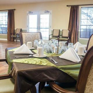 An elegant dining room with a neatly set table featuring folded napkins and glassware.