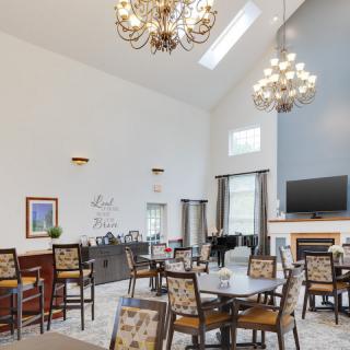 A spacious dining room with elegant chandeliers, round tables, and a cozy fireplace.