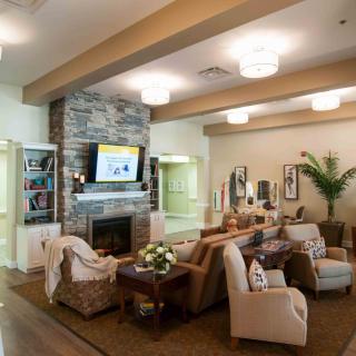A cozy living room with a stone fireplace, comfortable seating, and a television mounted above the mantel.