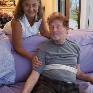 A woman and a man sitting together on a couch, smiling at the camera.