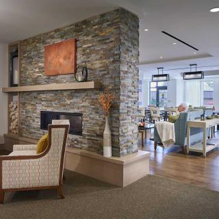 A modern living room with a stone fireplace and adjacent dining area.