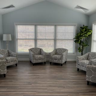 A modern living room with patterned chairs, large windows, and wood flooring.