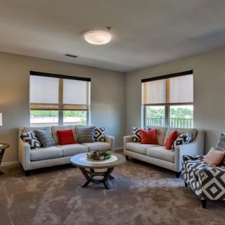 A modern living room featuring two sofas, a central coffee table, and large windows.
