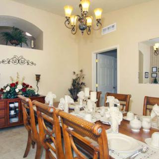 A well-decorated dining room with a large wooden table and matching chairs, adorned with elegant table settings and a chandelier overhead.