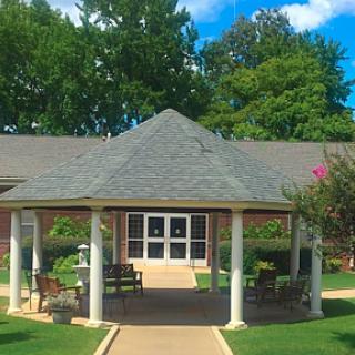 A serene gazebo surrounded by lush greenery and a well-maintained pathway.
