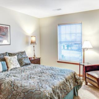 A cozy bedroom with a comfortable bed, soft lighting, and a window letting in natural light.