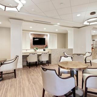 A modern lounge area featuring elegant seating with neutral tones and a large screen on the wall.