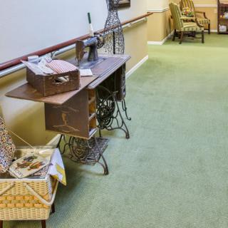 A hallway with vintage furniture and a green carpet, featuring a wooden desk and seating area.