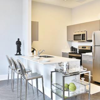 A modern kitchen with a sleek island counter, stainless steel appliances, and contemporary bar stools.