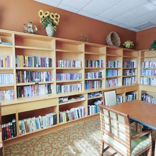 A cozy library room with wooden bookshelves filled with books and a table for reading.