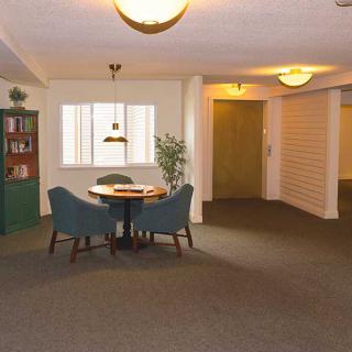 A cozy interior space with a table and chairs, a bookcase, and warm lighting.