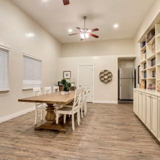 A stylish and spacious dining room featuring a large wooden table and white chairs, complemented by neutral walls and a cozy atmosphere.