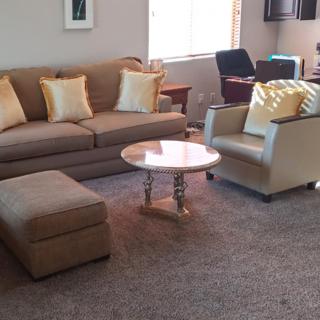 A cozy living room with a sofa, armchair, and round coffee table.