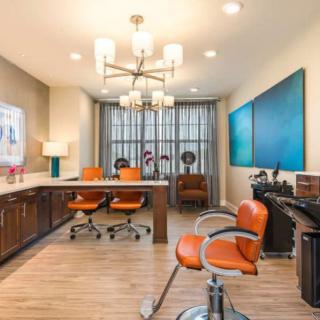 A modern office space featuring orange chairs, stylish lighting fixtures, and contemporary artwork on the walls.