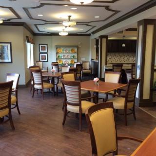 A cozy dining area with several tables and chairs, warmly lit with ceiling lights.
