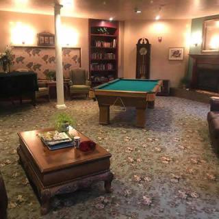 A cozy living room with a pool table and fireplace, featuring comfortable seating and warm lighting.