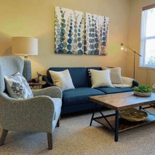 A cozy living room featuring a blue sofa, a grey armchair, and a wooden coffee table with modern decor.