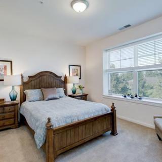 A cozy and well-lit bedroom featuring a wooden bed frame and matching nightstands.