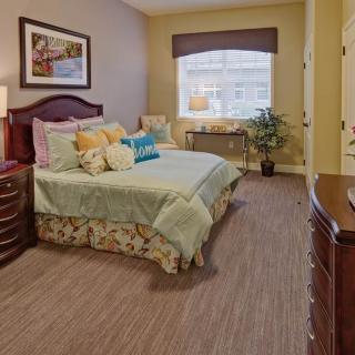 A cozy bedroom interior with a large bed, nightstands, and warm lighting.