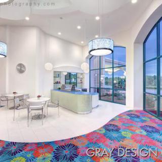 A modern and bright cafe interior with colorful carpet and large windows.