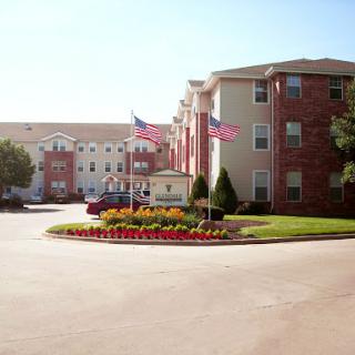 A well-maintained hotel entrance featuring colorful flowers and American flags.