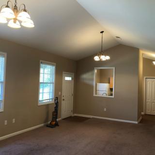 Spacious living room with carpet flooring and multiple light fixtures.