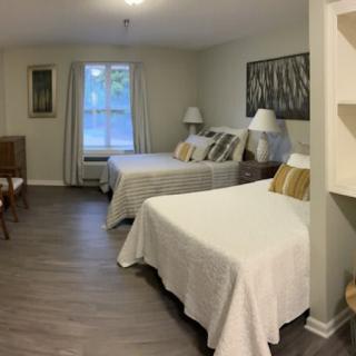 A modern hotel room featuring twin beds with neutral dcor and wooden flooring.