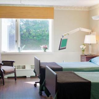 A well-lit hospital room featuring two patient beds and medical equipment.