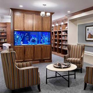 A cozy library seating area with an aquarium and bookshelves.