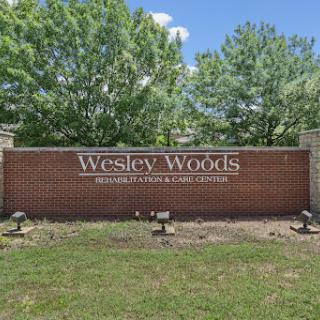 Entrance sign of Wesley Woods, surrounded by lush greenery.