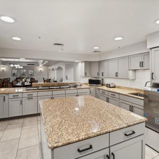 A spacious, modern kitchen featuring a large granite island and ample cabinetry.