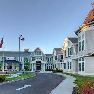 A large residential-style building with a circular driveway and flags at the entrance.